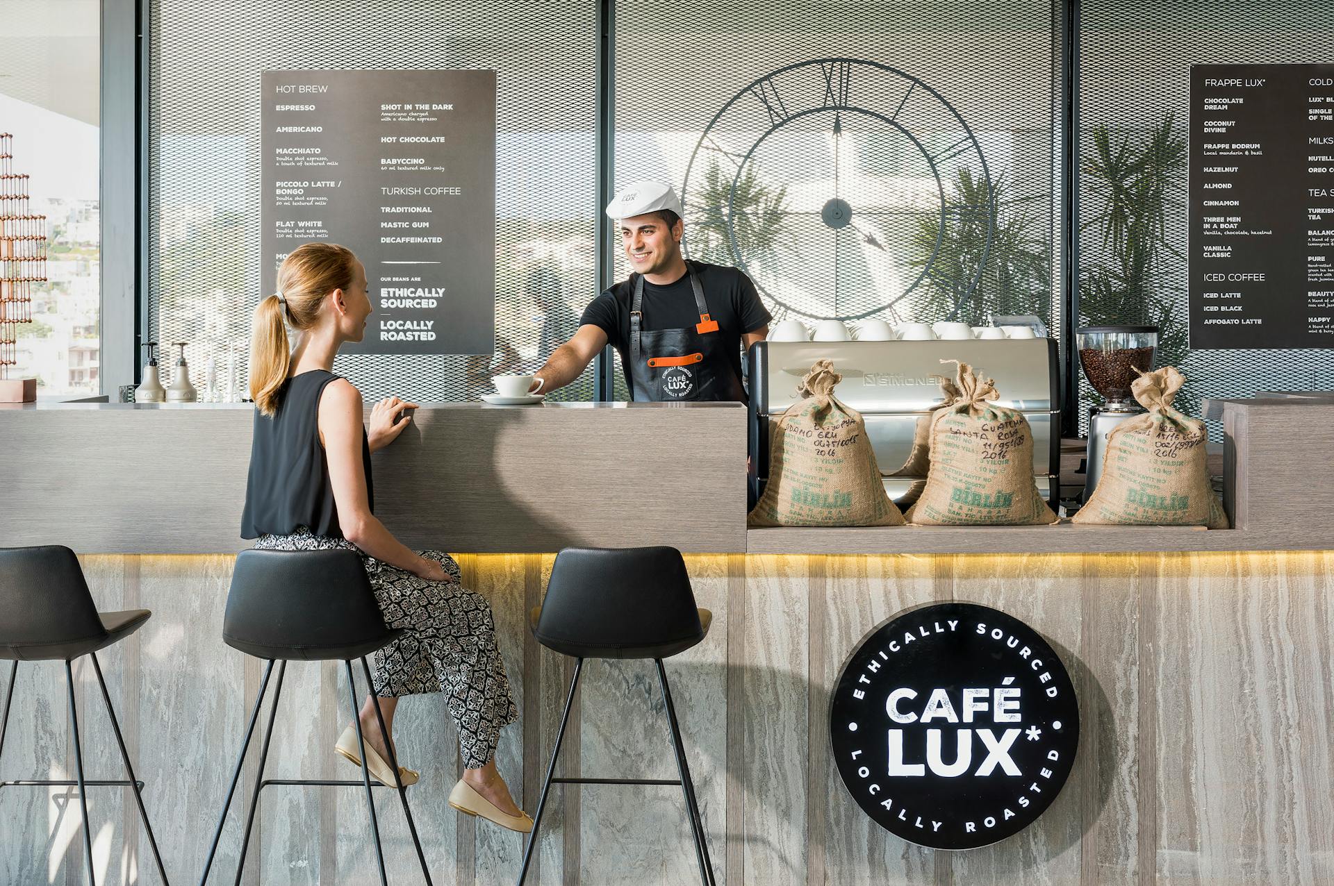 Barista serving coffee to a customer at Café Lux in Bodrum, Turkey.