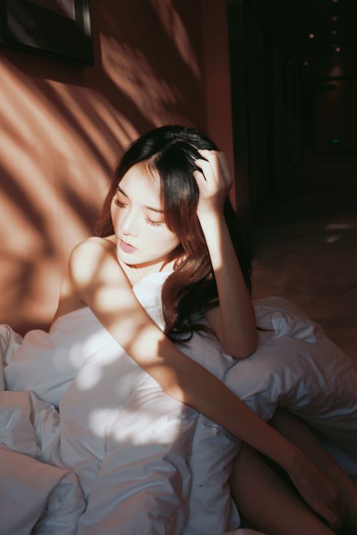 Free Asian woman sitting with soft lighting, creating a serene and intimate mood. Stock Photo