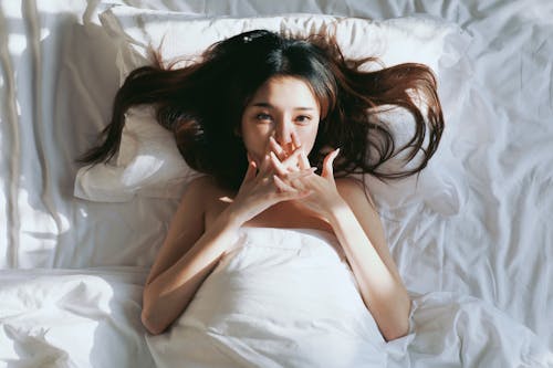A woman is laying in bed with her mouth open