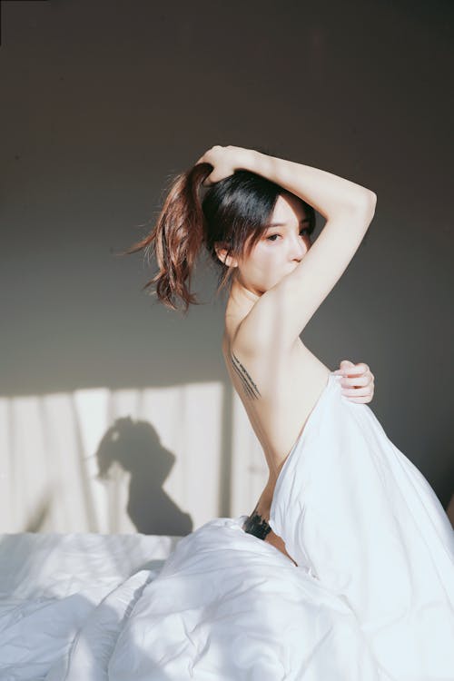 A woman in a white sheet is laying on a bed