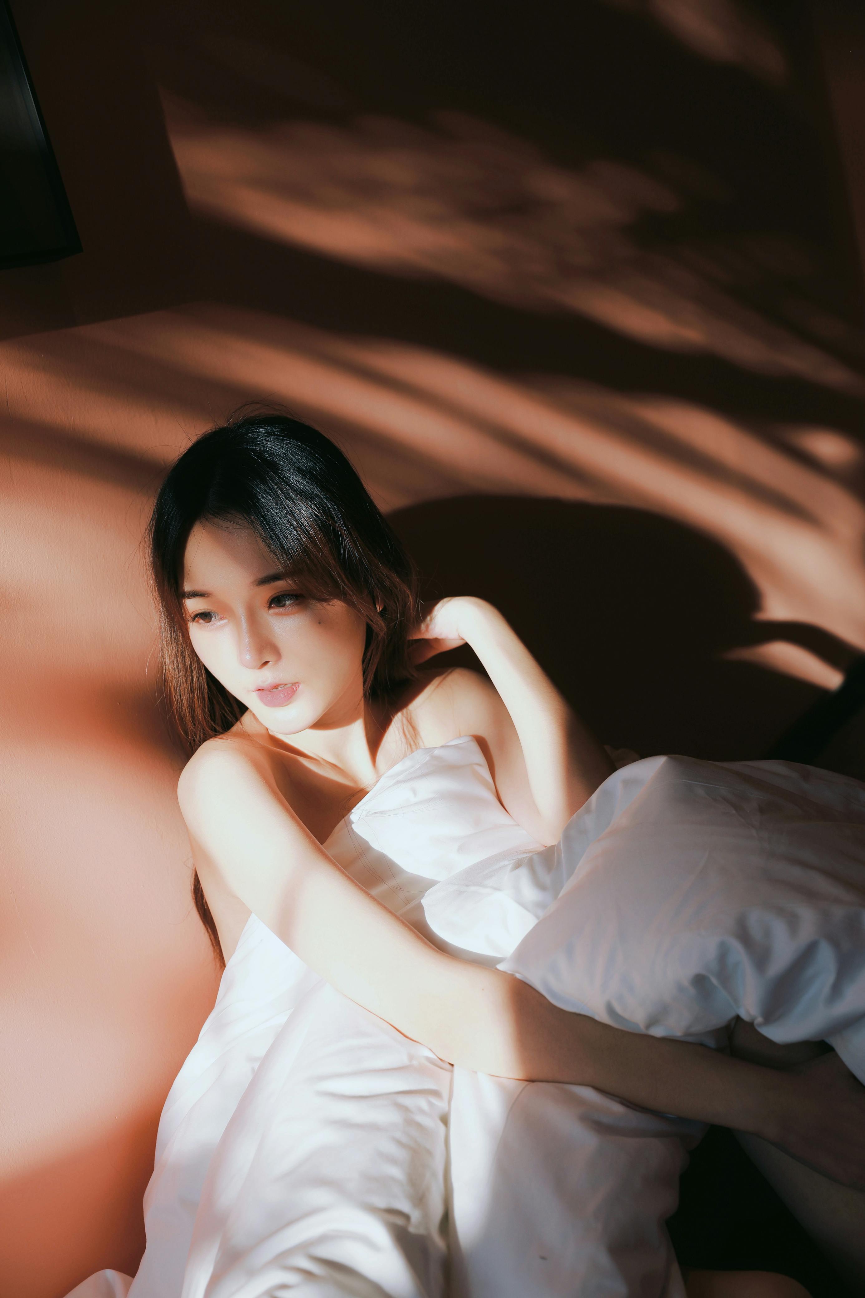 Soft morning-like light filtering through sheets, evoking intimate calm and sensual repose