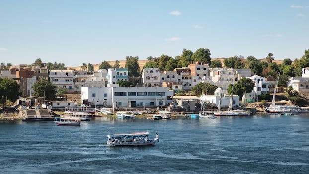 Captivating view of Aswan's riverside with traditional boats and houses along the Nile River.