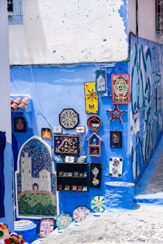Vibrant street art and mosaics adorn a blue-walled alley in a charming Moroccan town.