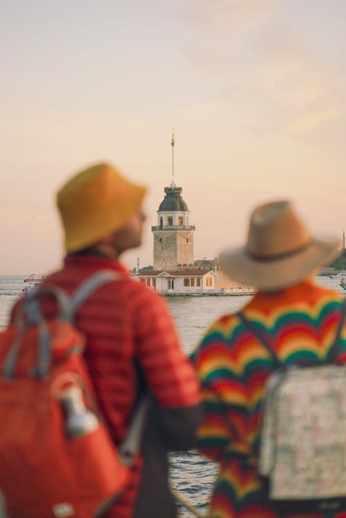 Two people with backpacks looking at a lighthouse