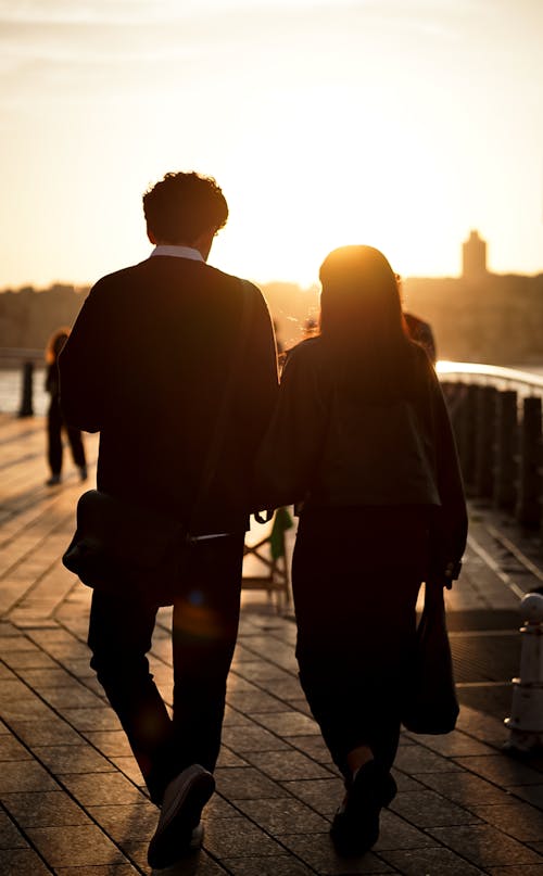 A couple walking along a pier at sunset