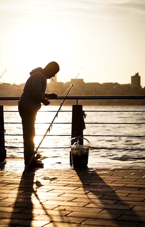A man fishing on the pier at sunset