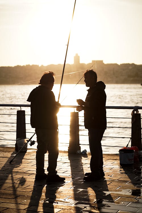 Two men standing on a pier with fishing rods