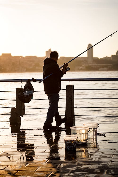 A man fishing on the water at sunset