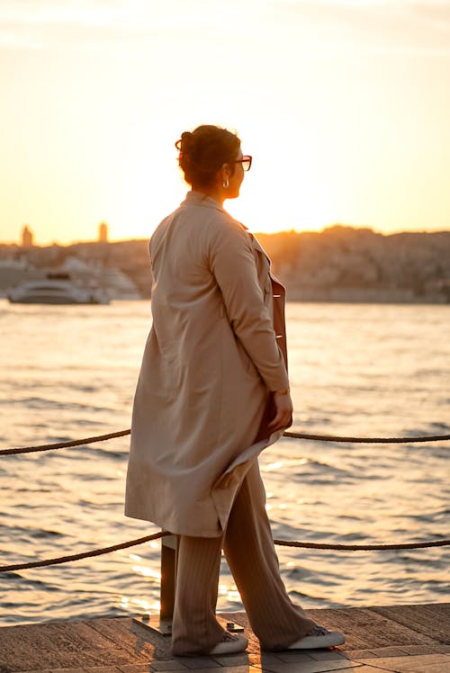 A woman standing on a pier looking at the sunset