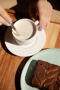 Close-up of a cozy coffee setup with a slice of chocolate cake on a table.