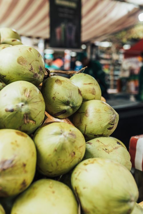 Free Close-up of fresh green coconuts stacked in a vibrant outdoor market setting. Stock Photo