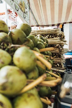 Close-up of fresh coconuts and sugarcane at a vibrant food market stall.