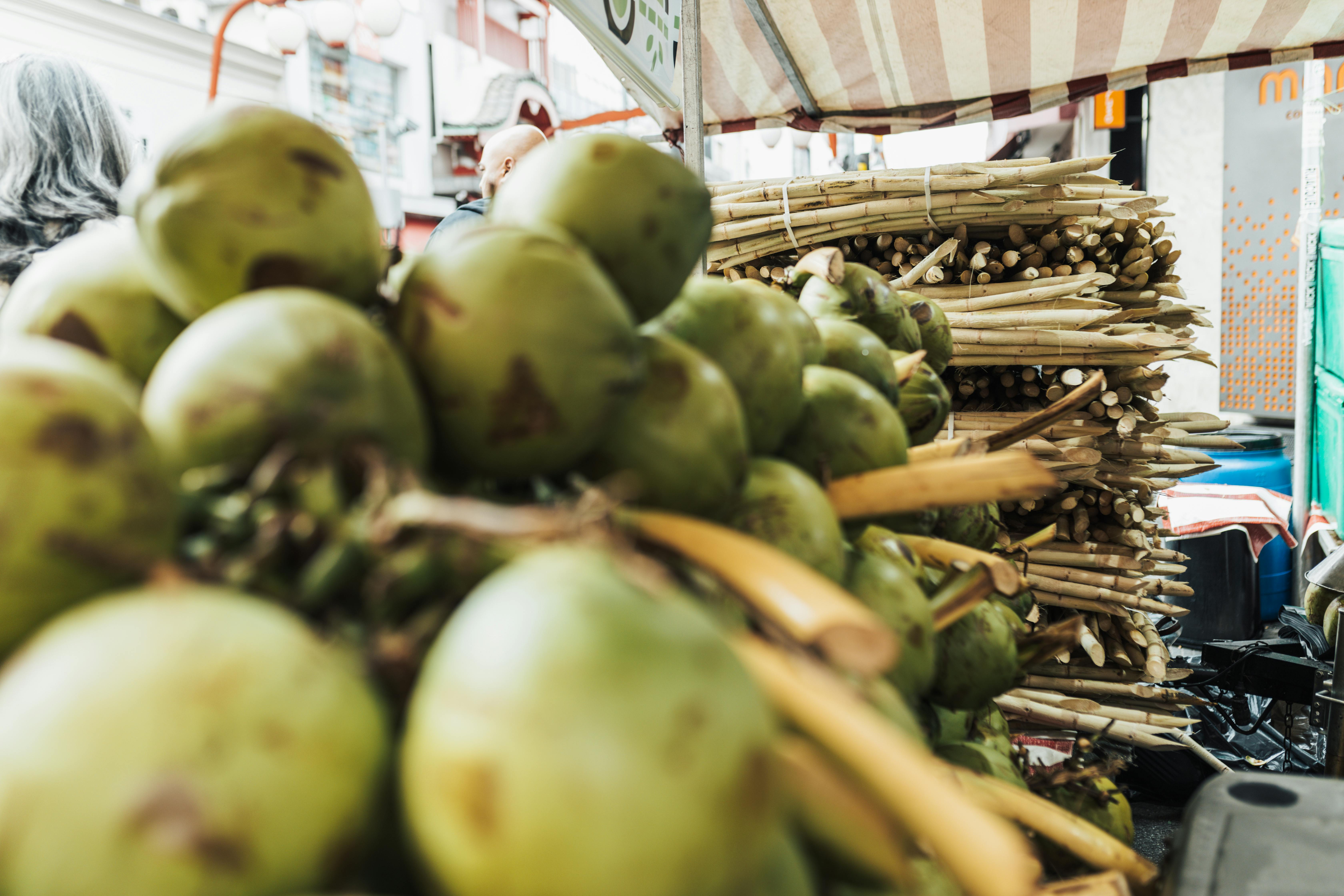 Colorful market display featuring fresh coconuts and sugarcane on bustling city street.