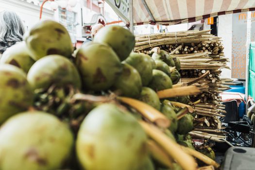 Colorful market display featuring fresh coconuts and sugarcane on bustling city street.