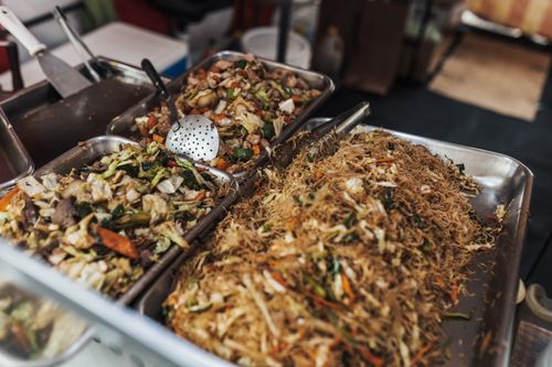Free A vibrant street food setup showcasing delicious Asian noodle dishes with vegetables and meat. Stock Photo