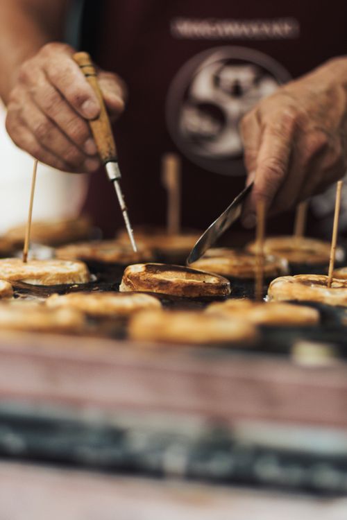 Free Close-up of a street vendor flipping pancakes at an outdoor market with skillful hands. Stock Photo