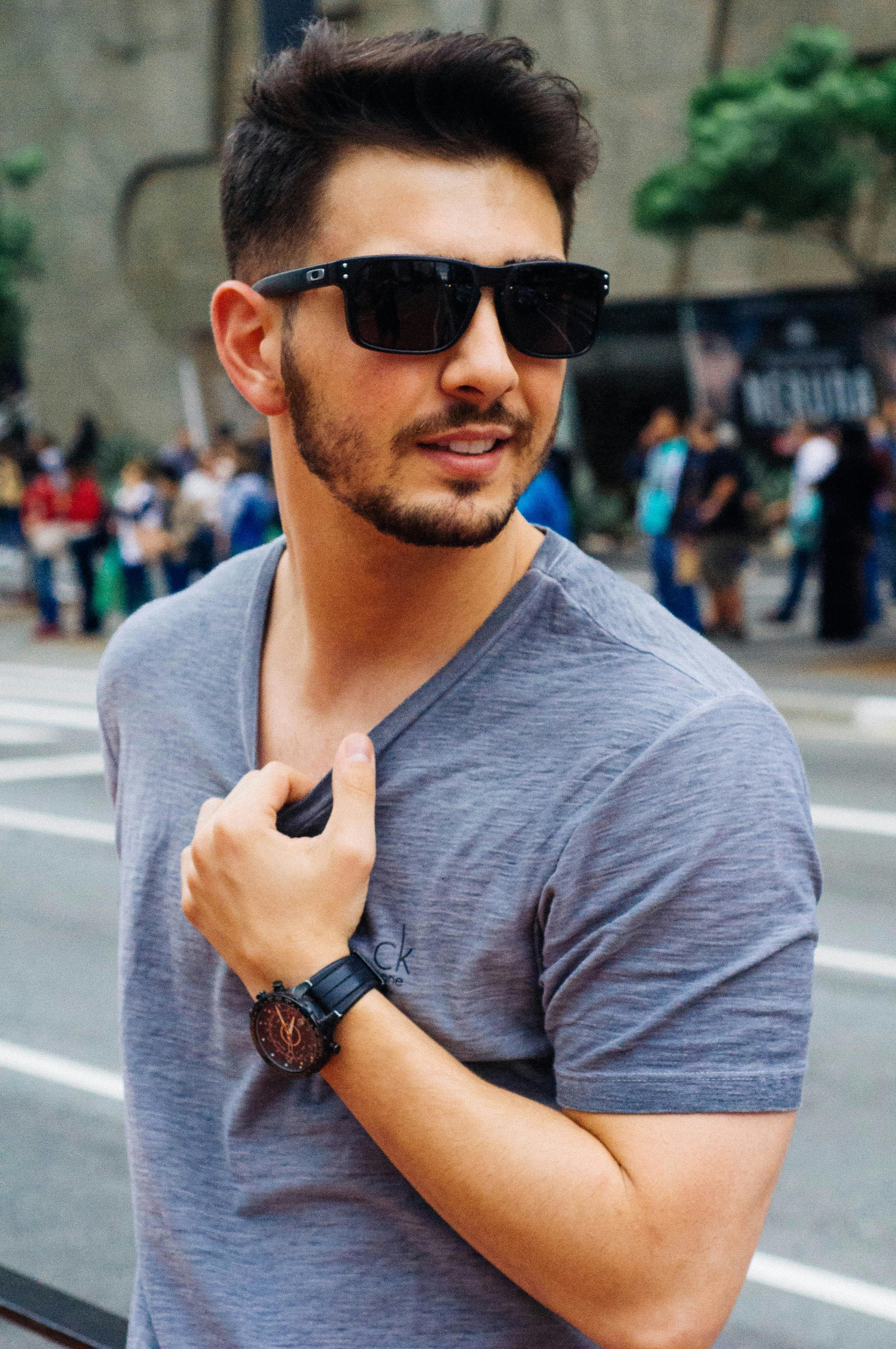 Casual portrait of a fashionable man wearing sunglasses in a bustling city street.