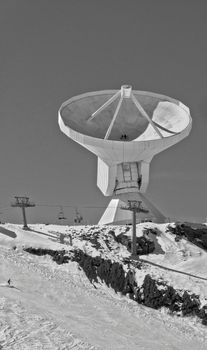 Black and white photo of a radio telescope in snowy Sierra Nevada, Spain.