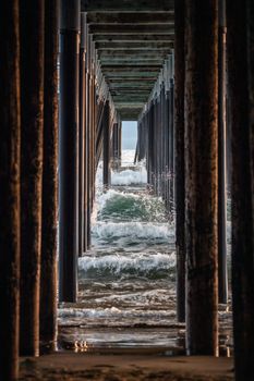 View of ocean waves crashing under Pismo Beach pier, California.