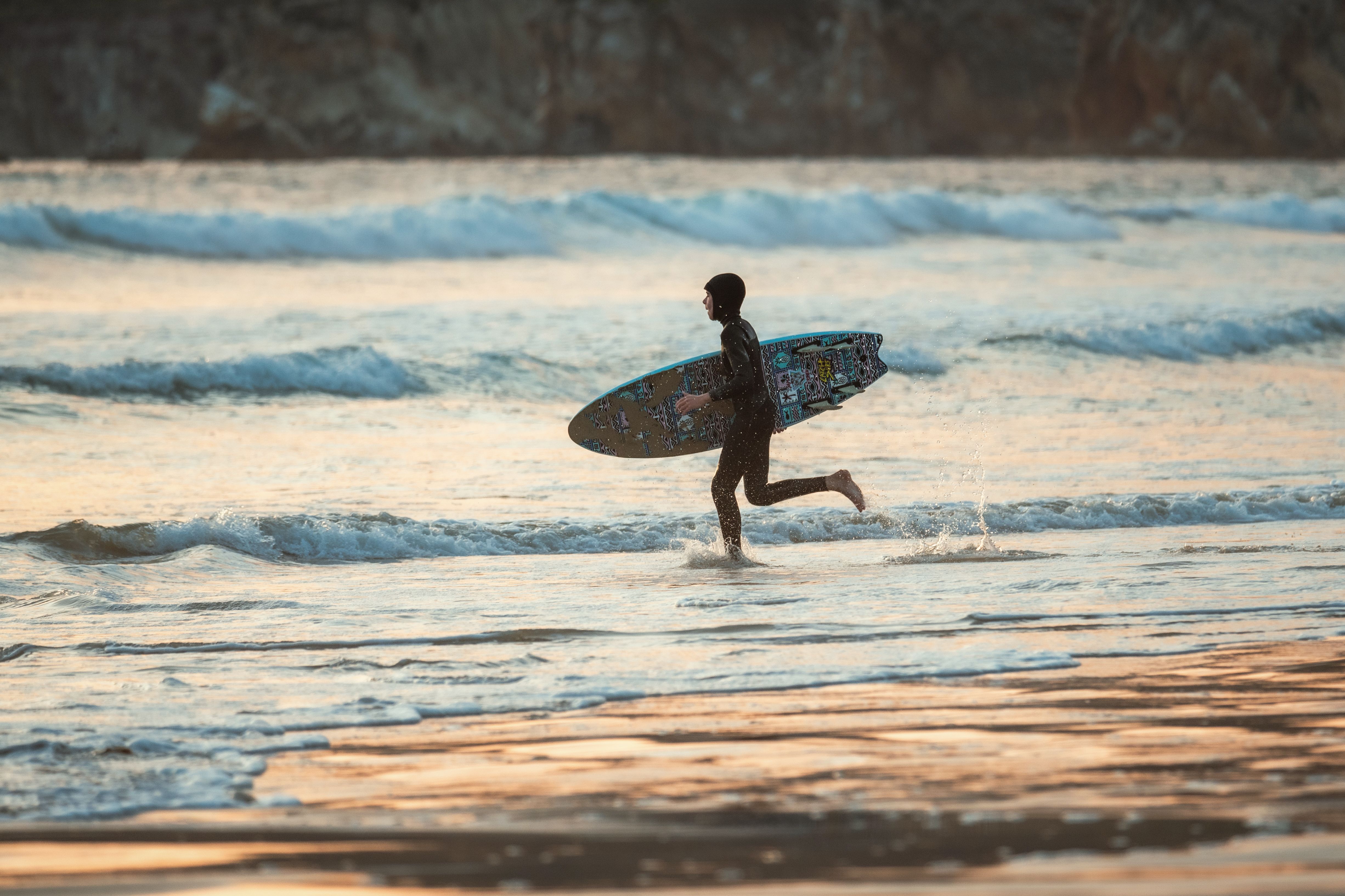 Surfer Running at the Coast with a Surfboard in Hand · Free Stock Photo
