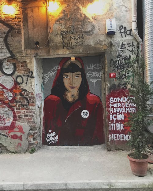 бесплатная Женщина в куртке с капюшоном рисует на закрытой двери, показывая освещенную уличную лампу Стоковое фото