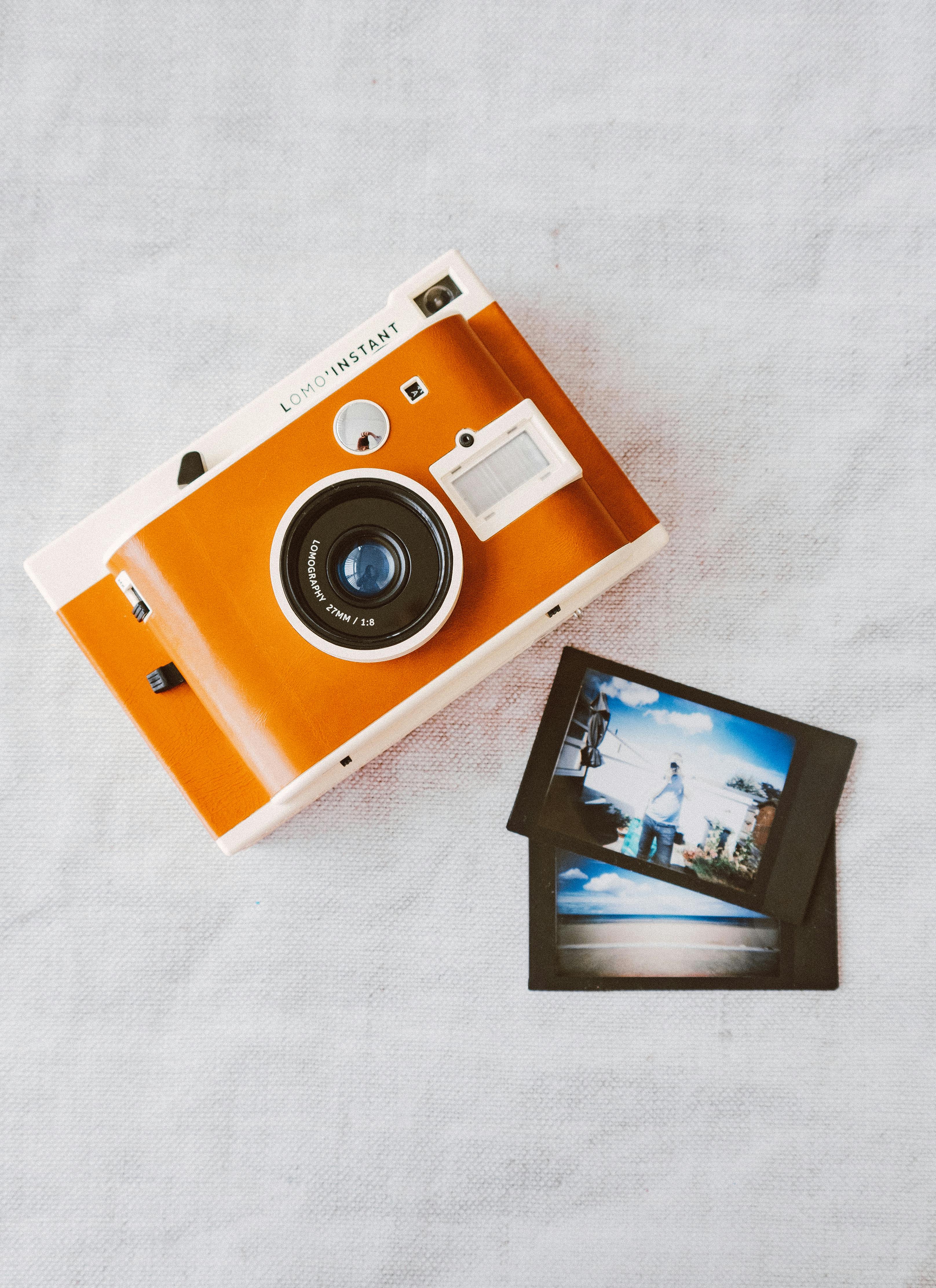 orange and white instant camera on white cloth