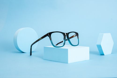 Free Stylish eyeglasses displayed on geometric shapes with a blue minimalist theme. Stock Photo
