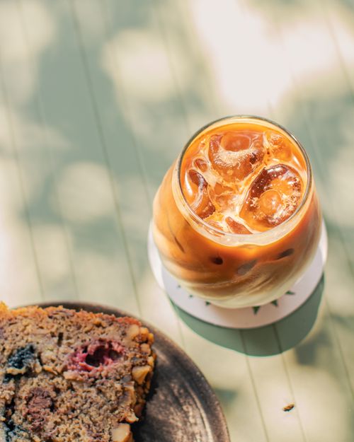 Free Refreshing iced coffee and dessert slice in bright sunlight, perfect for a summer indulgence. Stock Photo