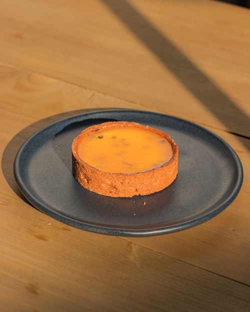 Free Golden egg custard tart on a ceramic plate, captured in warm natural light, perfect for food photography. Stock Photo