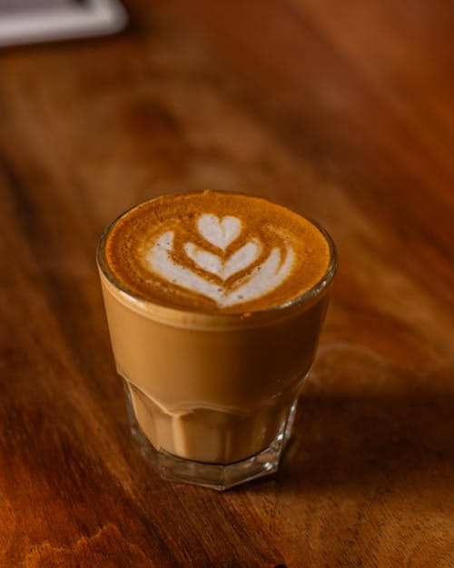 A latte is shown on a wooden table