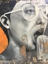 一幅描绘戴眼镜、张着嘴的人的生动肖像，为街头壁画增添了活力