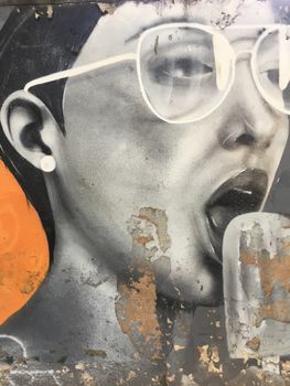一幅描绘戴眼镜、张着嘴的人的生动肖像，为街头壁画增添了活力