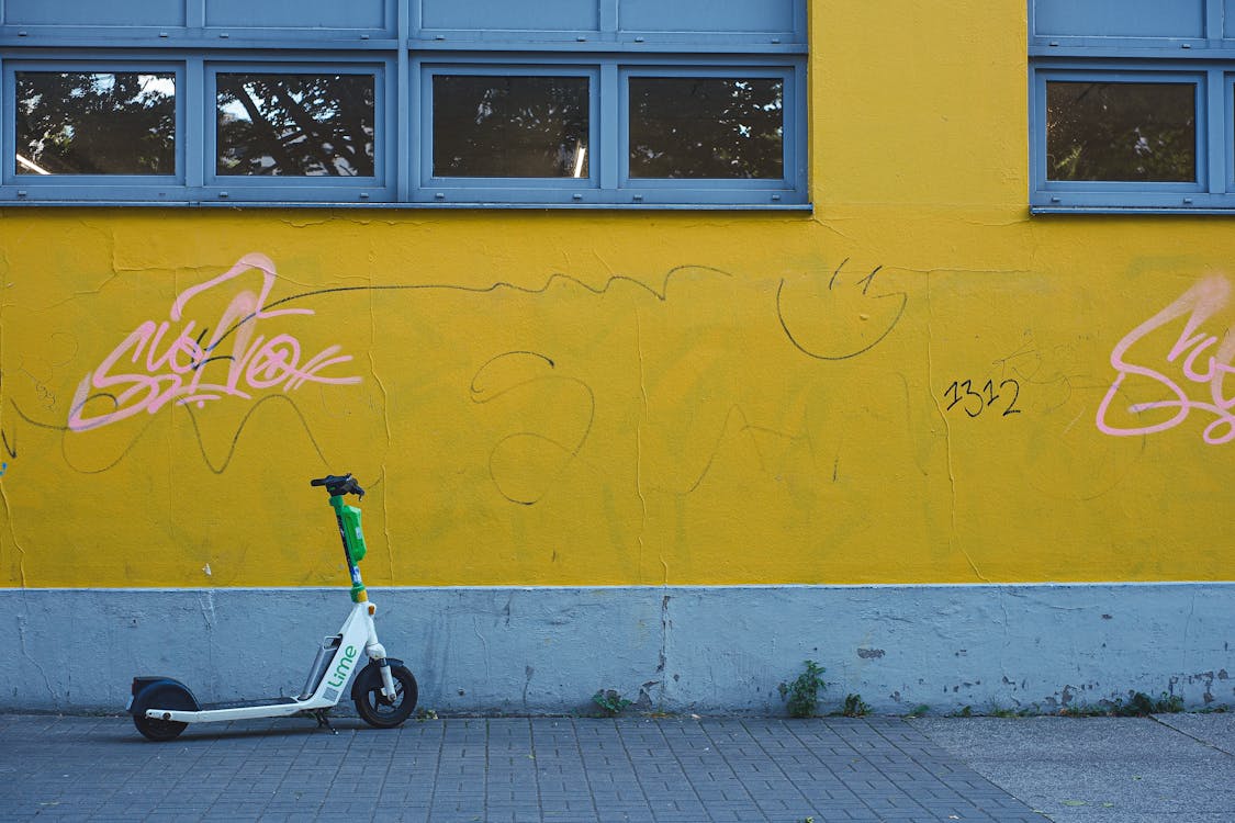 Free A scooter parked next to a yellow wall Stock Photo