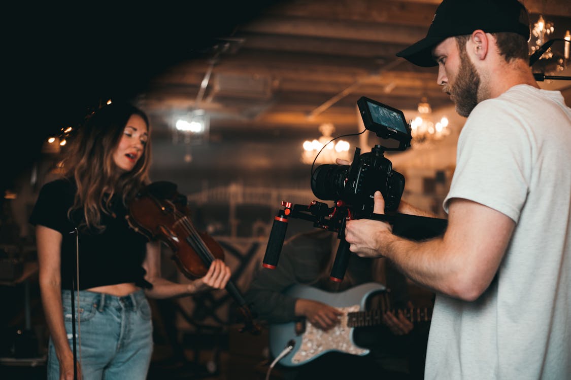 Free Man Taking a Video of a Woman Carrying a Violin Stock Photo