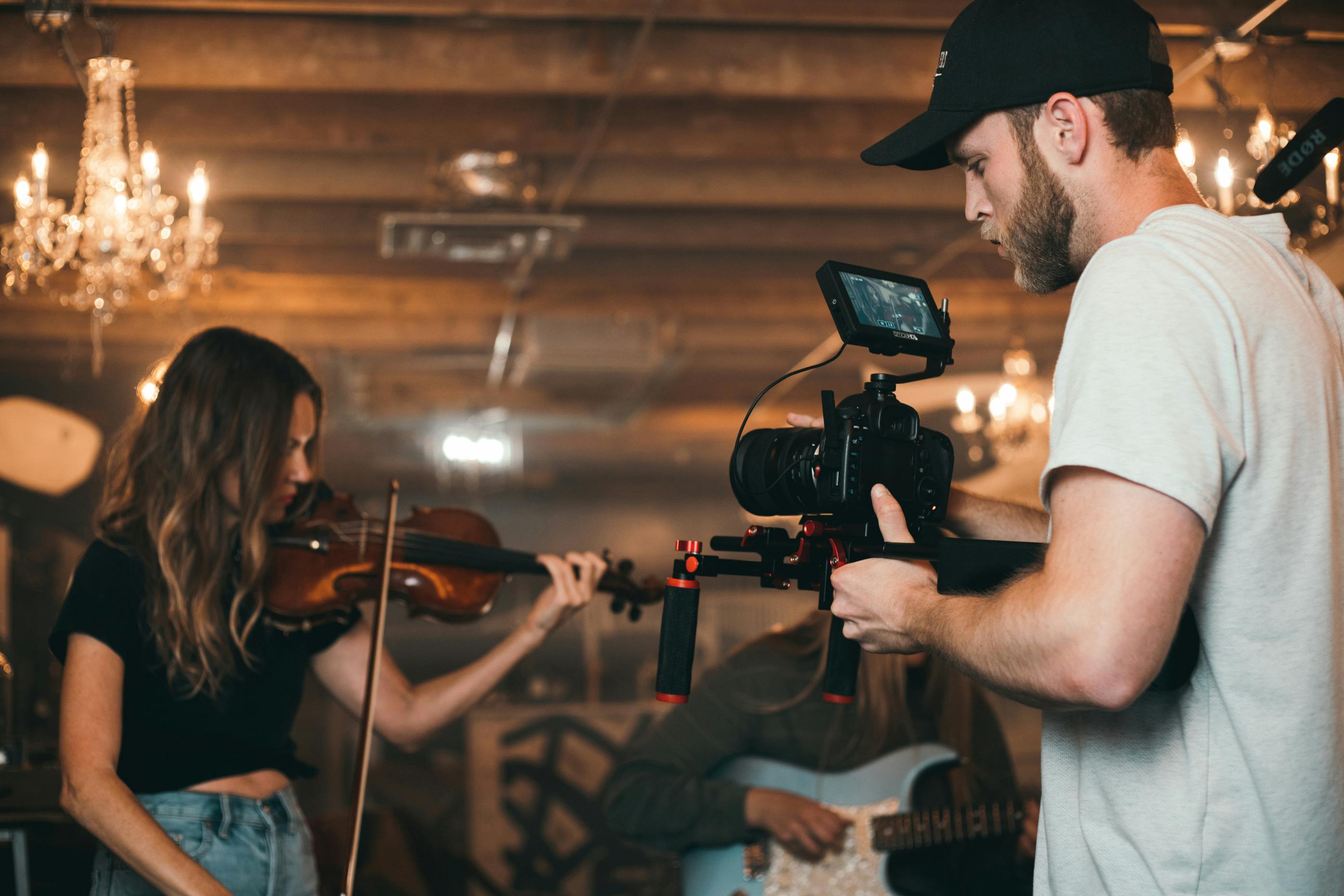 man holding camera and woman playing violin