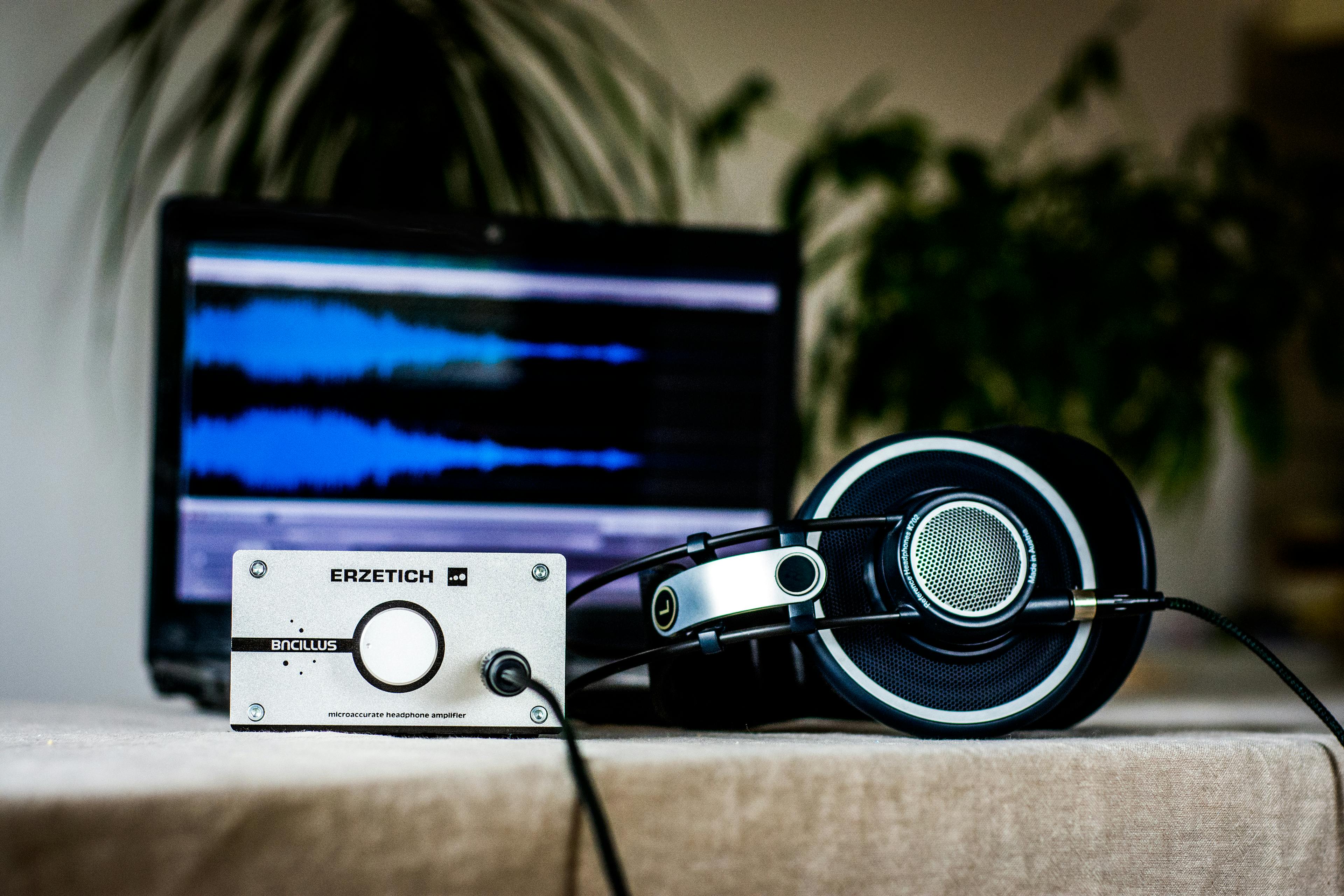 A sleek setup featuring headphones and an amplifier in front of a sound editing laptop, ideal for audio professionals.
