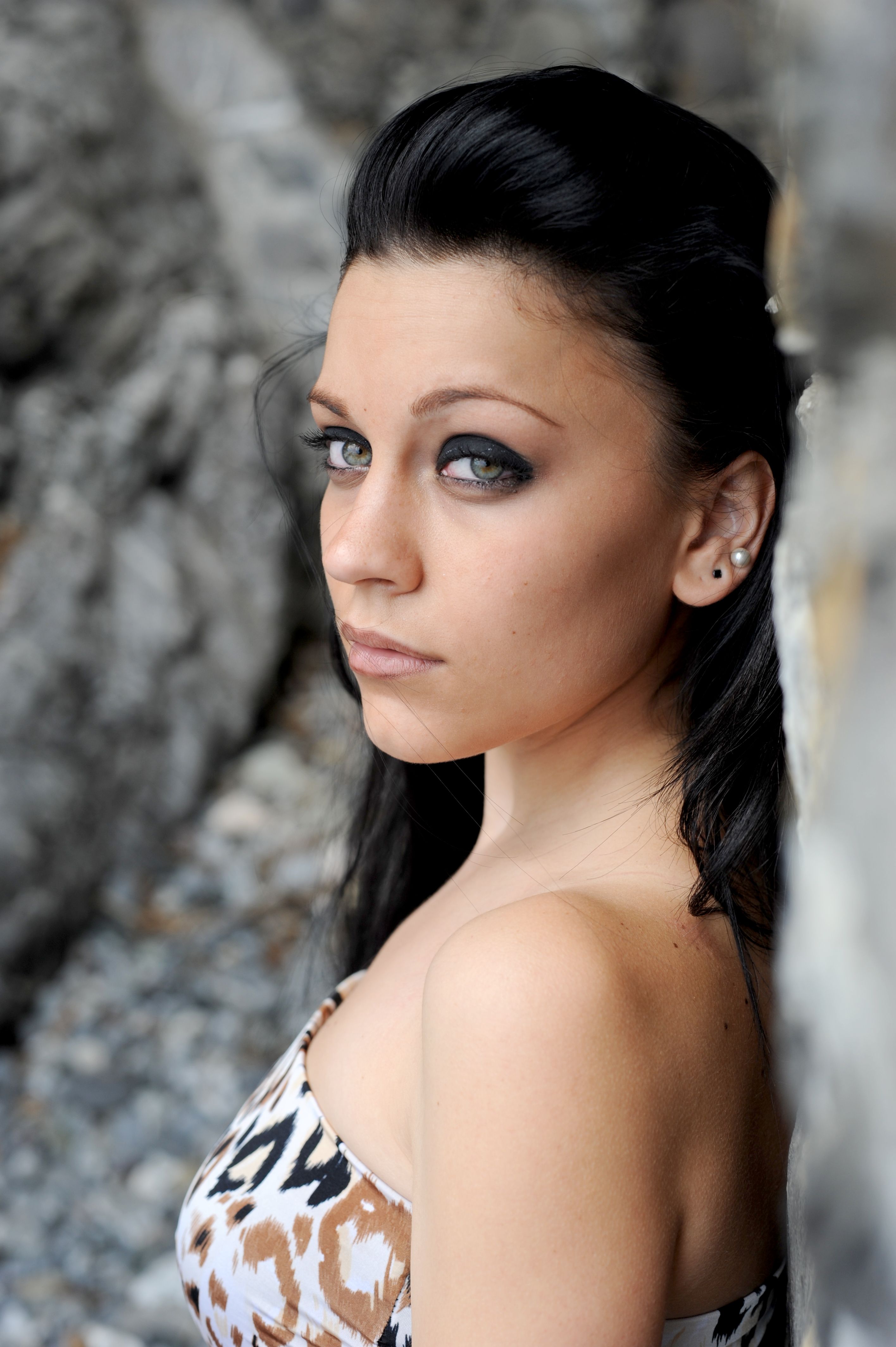 Elegant portrait of a woman with smokey eye makeup in an outdoor setting.