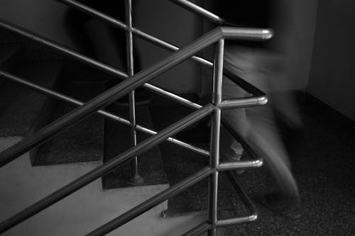 Two People Walking on Staircase with Steel Railing