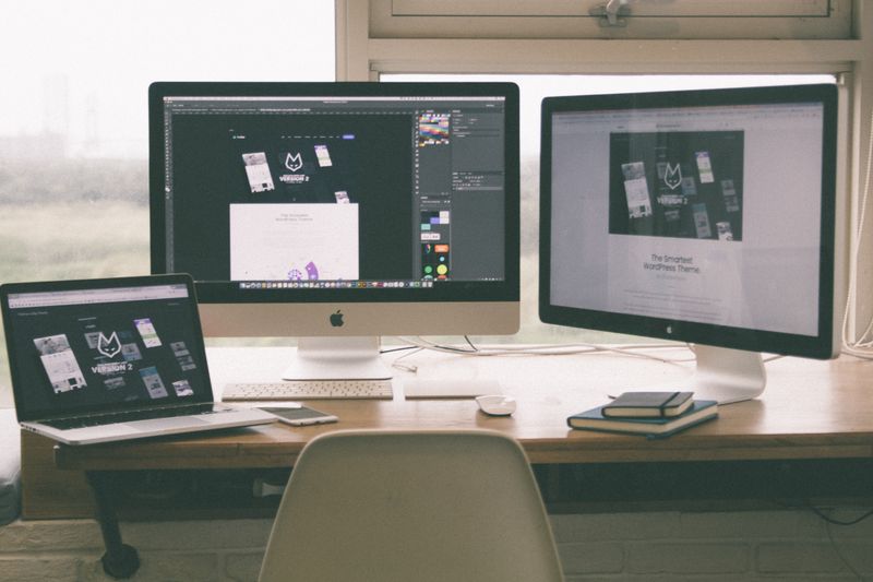 Stylish and efficient workspace with multiple monitors, laptop, and smartphone, showcasing a web design project.