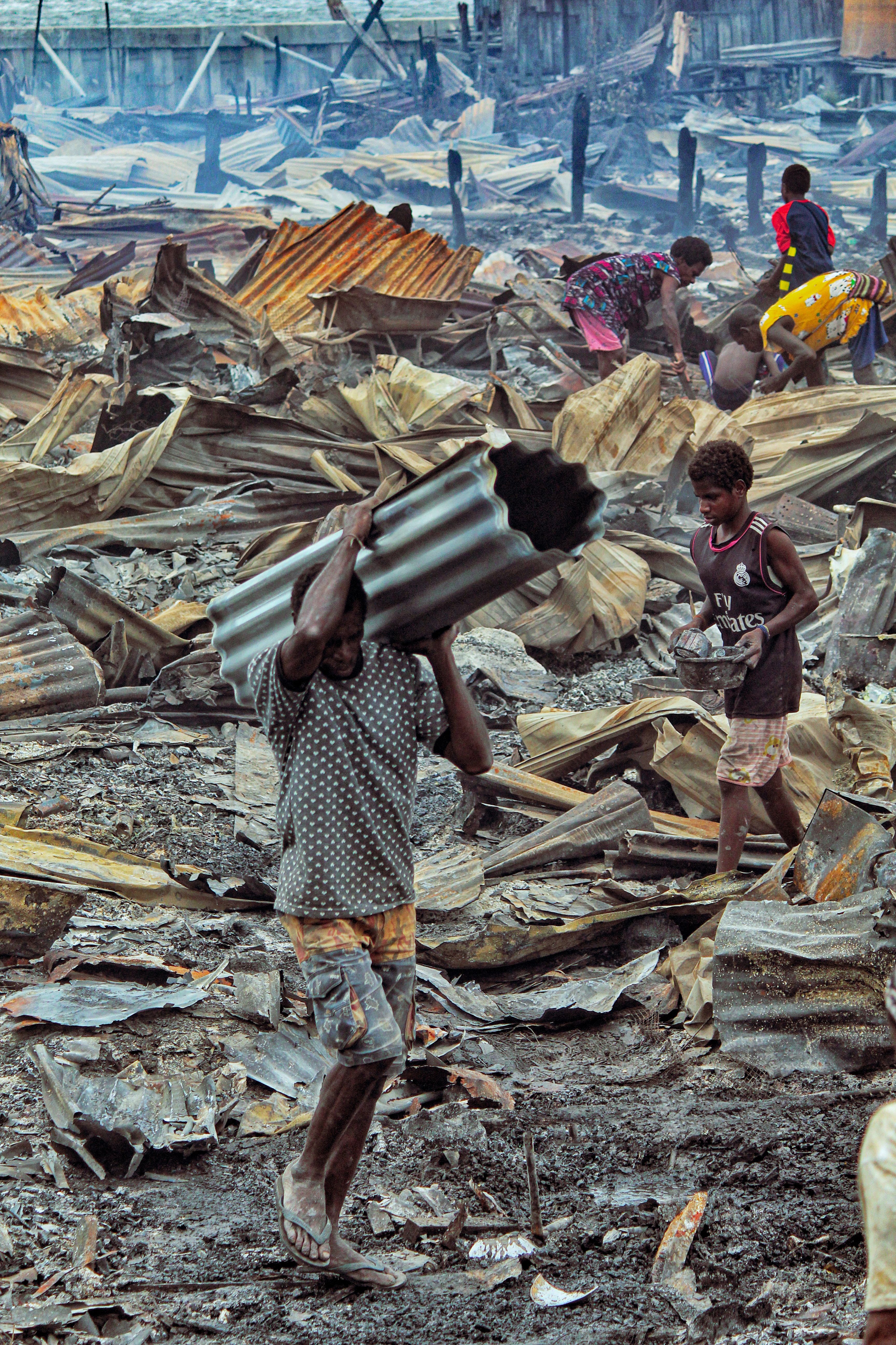 Workers salvage materials from debris in Agats, Papua, showcasing human resilience.
