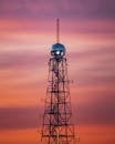 一座著名的通信塔矗立在充满活力的日落天空下，展现了现代电信技术