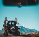 在山区背景下的乡村道路上，停着一辆红色拖拉机，体现了农村交通