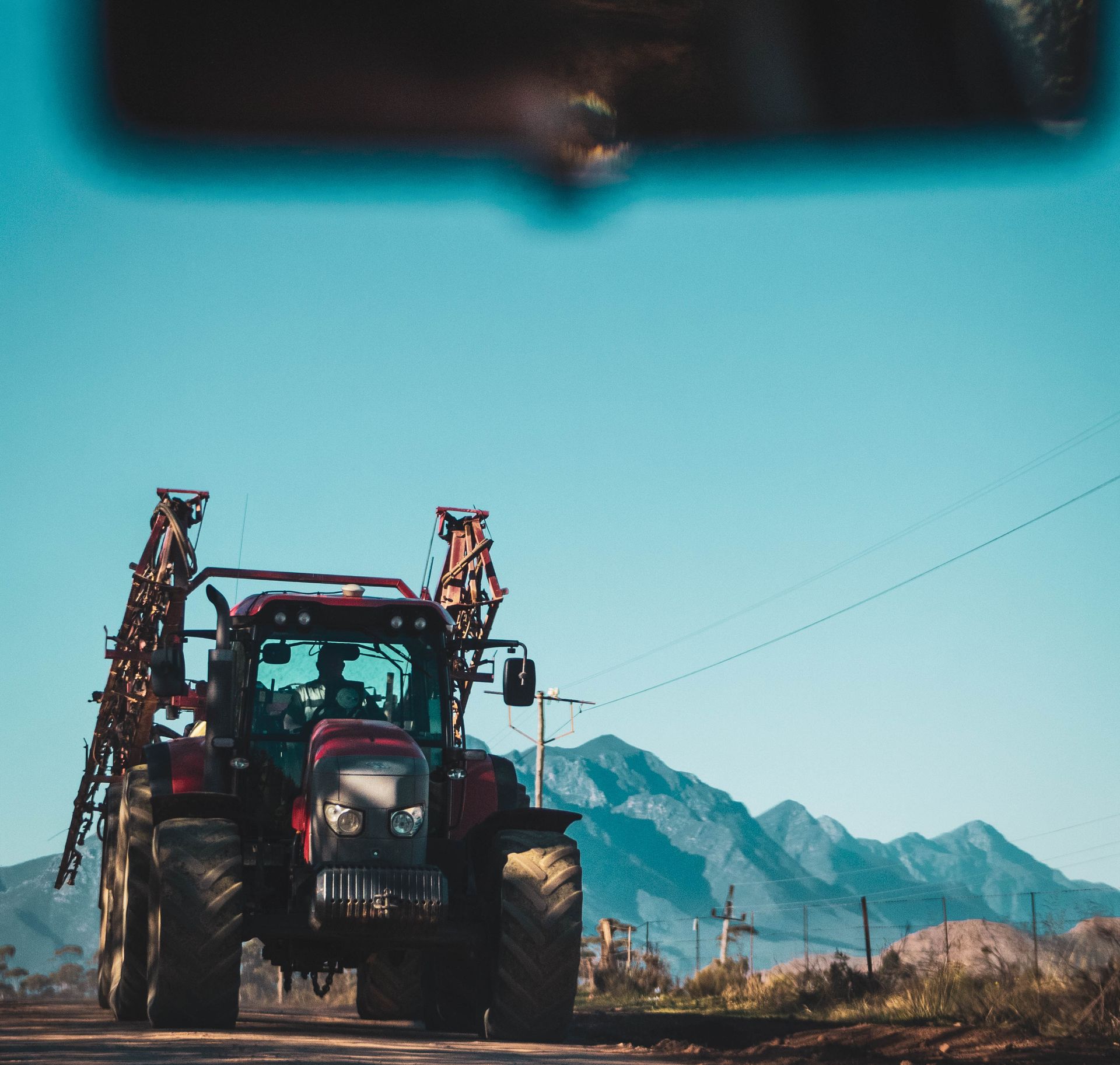 Red tractor on a country road against a mountainous backdrop, exemplifying rural transportation.