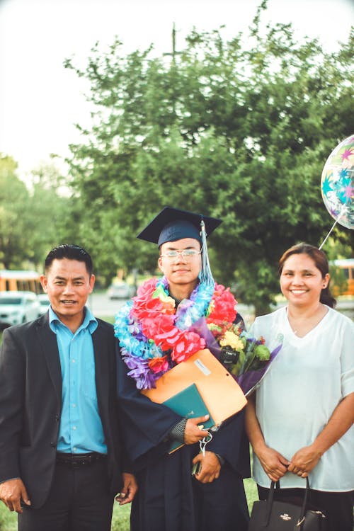 Photo of a Man Wearing Academic Gown Together with His Parents