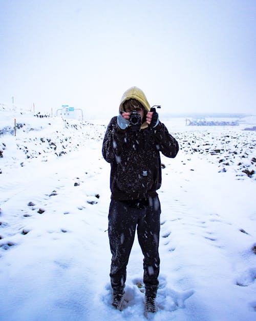 一個人在積雪的地面上拿著照相機的照片