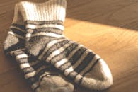 阳光明媚的木地板上，温暖的针织条纹袜子营造出舒适时尚的冬季氛围