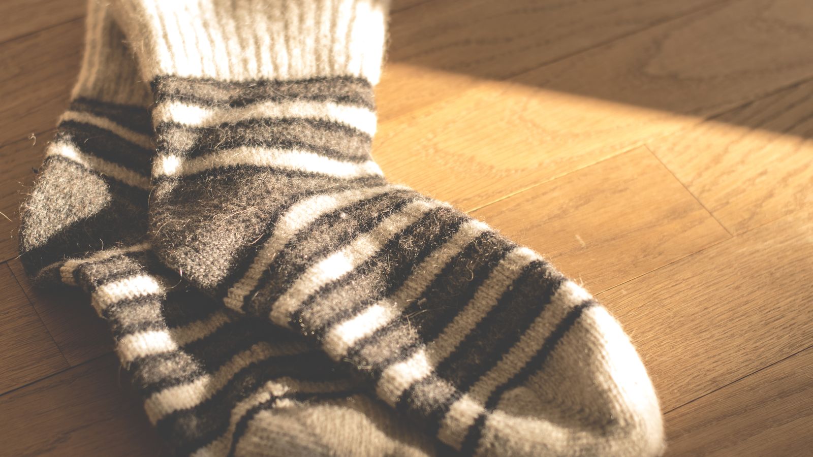 Striped knitted socks on a sunlit wooden floor