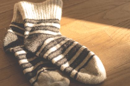 Warm knitted striped socks on a sunlit wooden floor — photo by Lum3n on Pexels
