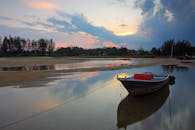 日落时分，一艘渔船停在宁静的湖面上，倒映着充满活力的天空