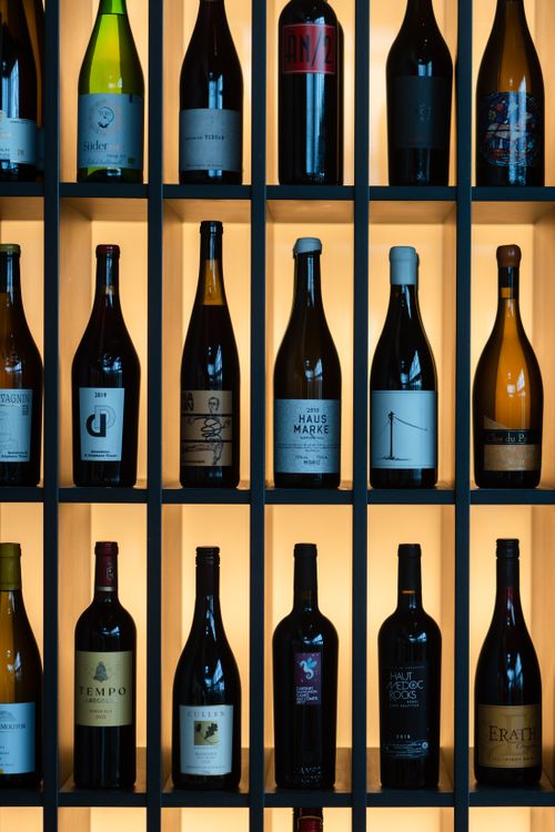 Free A vertical arrangement of diverse wine bottles on a backlit shelf displaying elegance and variety. Stock Photo